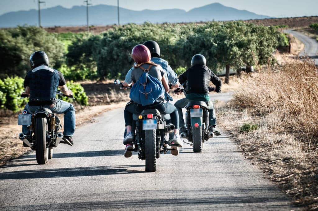 Rear view of four friends motorcycling on rural road, Cagliari, Sardinia, Italy