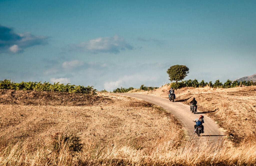 Rear view of four friends riding motorcycles on rural road, Cagliari, Sardinia, Italy
