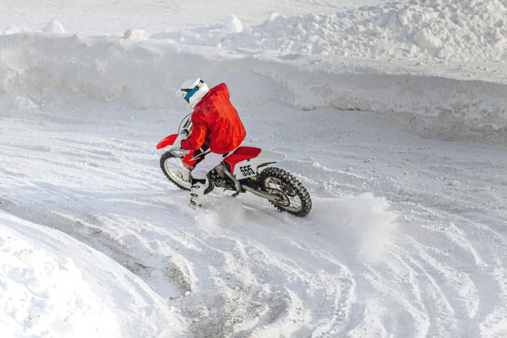 motorcycle racer on motorcycle riding snowy turn