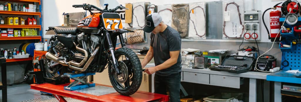 Mechanic man checking custom motorcycle over platform