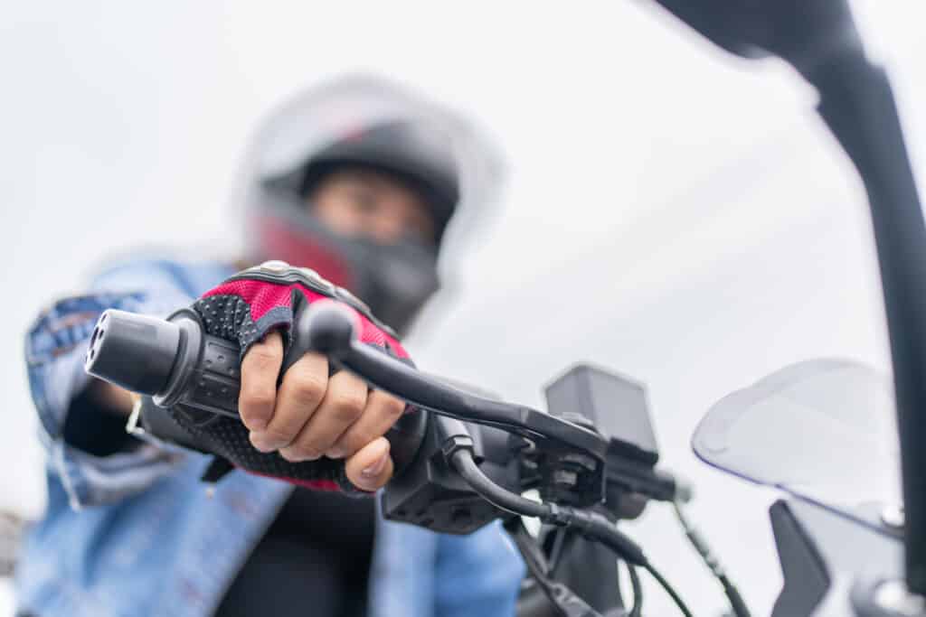 Close-up and focus on the hands of an hispanic female driver on a handlebar of a motorbike