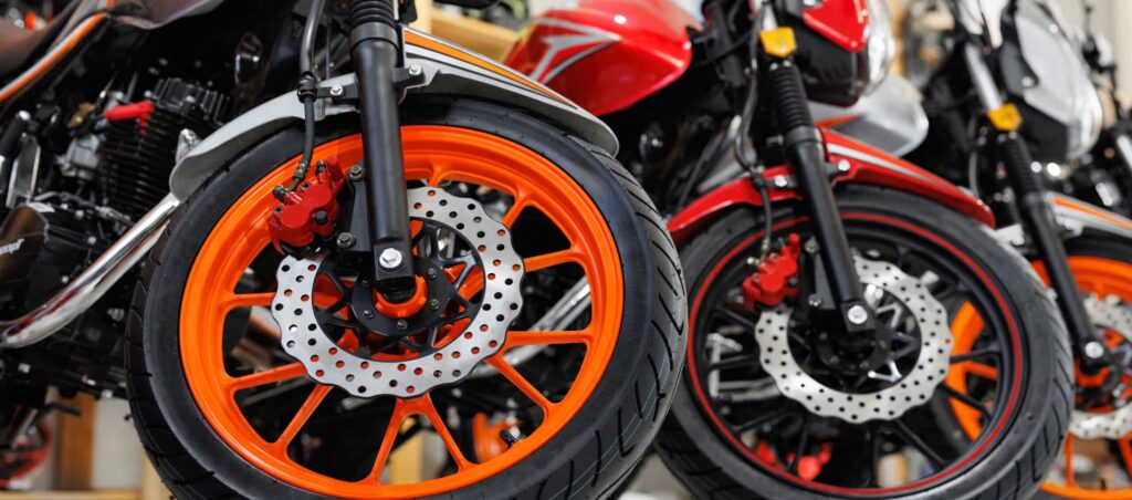 There are many colorful motorcycles for sale in exhibition hall. Wheels close-up