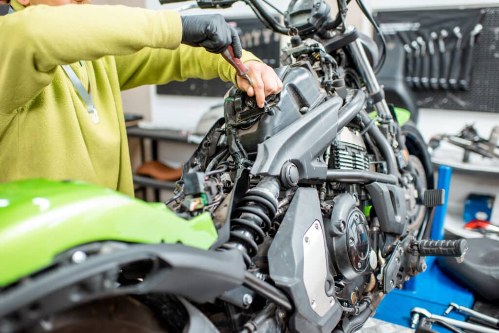 Worker repairing electric wiring in the motorcycle during a repairment at the workshop