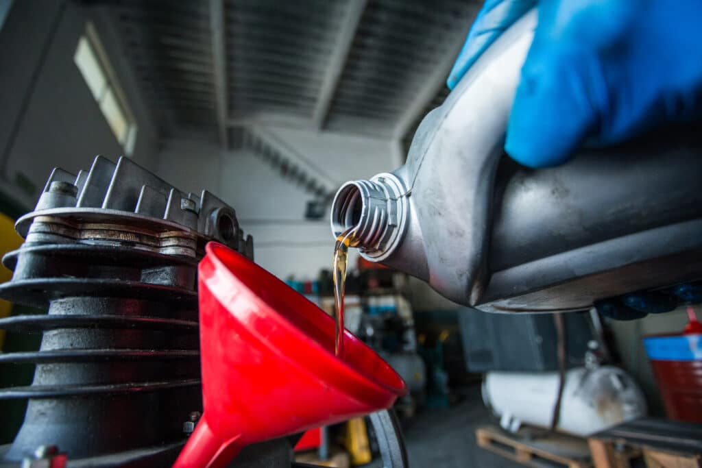 Close-up of a mechanic pouring oil into a compressor engine
