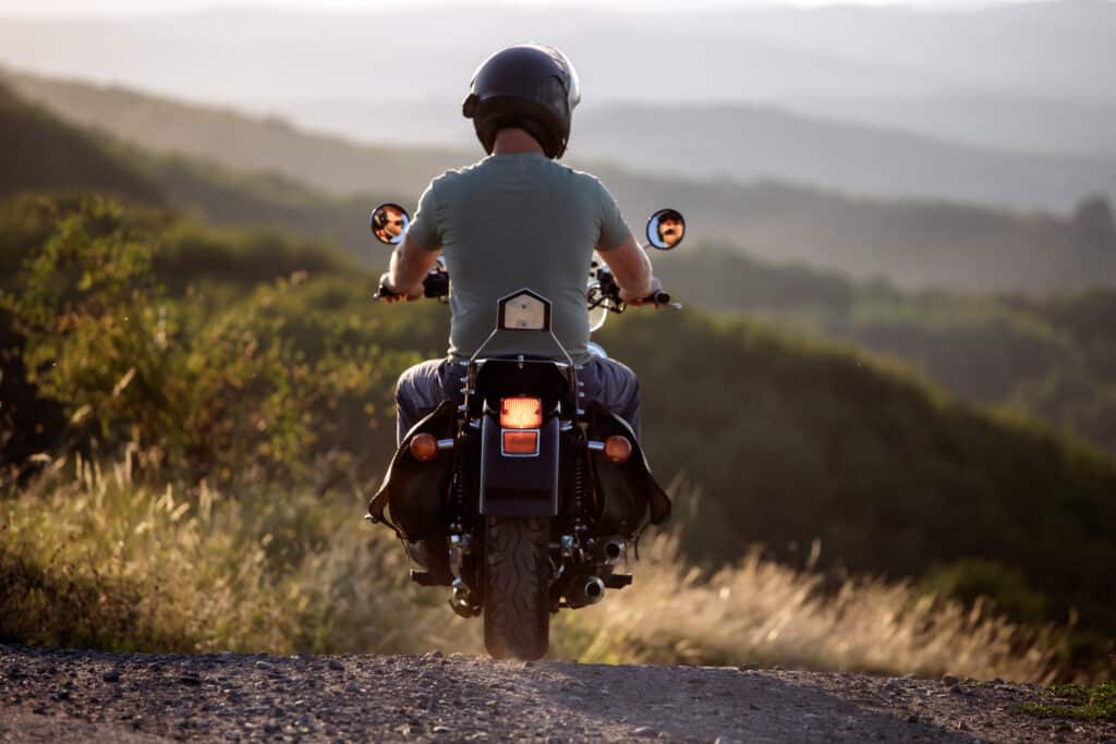 Motorcycle rider on the road in sunset light. Travel and sport, speed and freedom concept