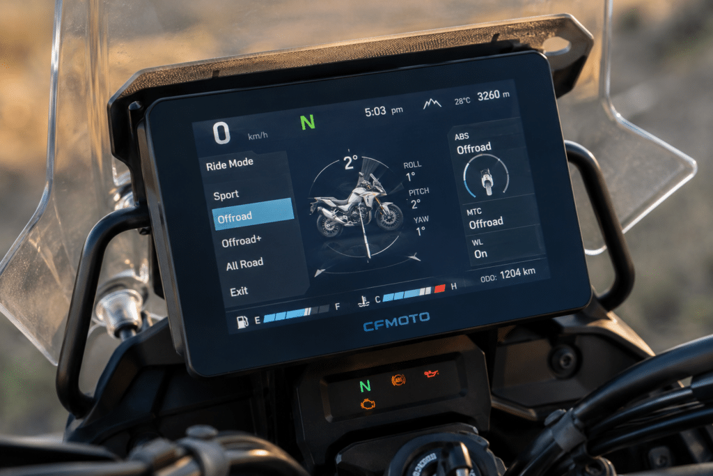 photorealistic close-up of CFMoto 800 MT-X dashboard showing TFT screen with riding modes and IMU electronics active, modern adventure bike instrumentation, sharp technical detail, dramatic sidelight, no watermark