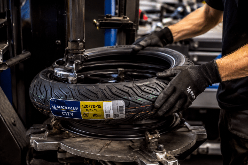 close-up of scooter tire change workshop, 120/70-15 tire being mounted on a scooter wheel